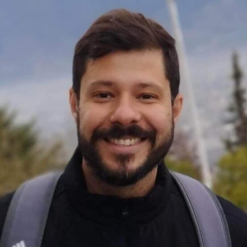 Homem branco de cabelo curto e barba castanha, sorrindo levemente.